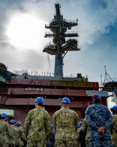 Sailors assigned to the Nimitz-class aircraft carrier USS George Washington (CVN 73) look up at the newly installed main mast during the mast-stepping ceremony on George Washington's flight deck during its four-year refueling and complex overhaul process. (Photo: U.S. Navy)