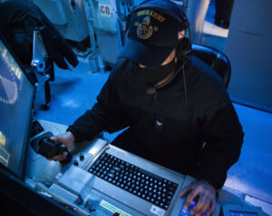 Fire Controlman Second Class Marcos Reyes, assigned to guided missile destroyer USS Barry (DDG-52), stands gun fire control system watch in the ship’s combat information center during bi-lateral exercise Resilient Shield 2021. (Photo: U.S. Navy, by Ens. Emilio Mackie)
