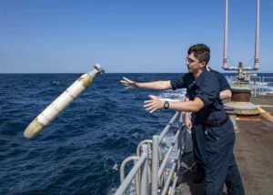 Sonar Technician (Surface) Seaman Apprentice Isaiah Garcia deploys a MK 39 EMATT (Expendable Mobile ASW Training Target) from the fantail of the guided-missile cruiser USS Normandy (CG-60) as part of an anti-submarine warfare exercise during International Maritime Exercise 2019 (IMX 19) in November 2019. (Photo: U.S. Navy by Mass Communication Specialist 2nd Class Michael H. Lehman)