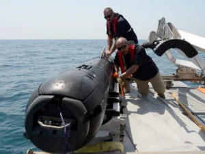 Civilian contractors secure an M18 Mod 2 Kingfish Unmanned Underwater Vehicle (UUV) to the deck of an 11-meter rigid hull inflatable boat in August 2012 for mine countermeasure operations in the U.S. 5th Fleet area of responsibility. (Phooto: U.S. Navy by Mass Communication Specialist 2nd Class Blake Midnight)