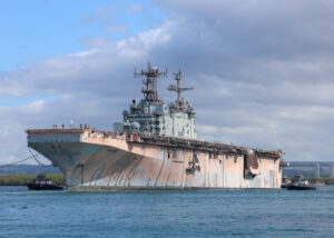 The decommissioned amphibious assault ship, ex-USS Tarawa (LHA-1), is escorted out of Pearl Harbor during Exercise Rim of the Pacific (RIMPAC) on July 16, 2024. (Photo: U.S. Navy by Mass Communication Specialist 2nd Class Courtney Strahan)