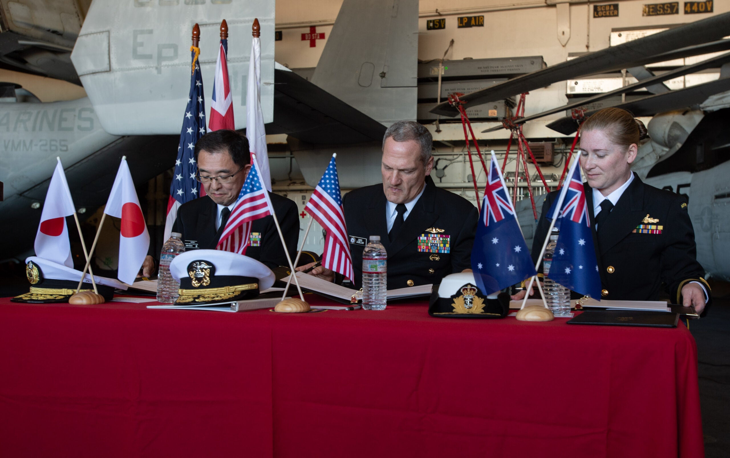 Rear Adm. Naoya Hoshi, Director General of Logistics Department, Maritime Staff Office, Japan Maritime Self Defense Force; Vice Adm. Jeff Jablon, Deputy Chief of Naval Operations for Installations and Logistics, OPNAV N4; and Commodore Catherine Rhodes, Director General Logistics, Royal Australian Navy, sign a Trilateral Terms of Reference aboard the forward-deployed amphibious assault ship USS America (LHA 6) on July 11, 2025. It focuses on commitments to supply chain collaboration and interoperability among the three navies. (Photo: U.S. Navy by Mass Communication Specialist 3rd Class Darian Lord)