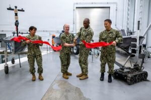From left to right, Vice Adm. Yvette Davids, Deputy Chief of Naval Operations for Operations, Plans, Strategy, and Warfighting Development, Chief of Naval Operations Adm. Daryl Caudle, Rear Adm. Melvin Smith, commander of Submarine Group Two (COMSUBGRU 2), and Lt. Cmdr. Johnny Kim, the senior attending representative for the Direct Reporting Portfolio Manager for Unmanned Systems, cut the ribbon at a ribbon cutting ceremony for the Robotic and Autonomous Systems Warfighting Development Center on Joint Expeditionary Base Little Creek-Fort Story in Norfolk, Va. on Sept. 24, 2026. (Photo: U.S. Navy by Mass Communication Specialist 1st Class John Bellino).