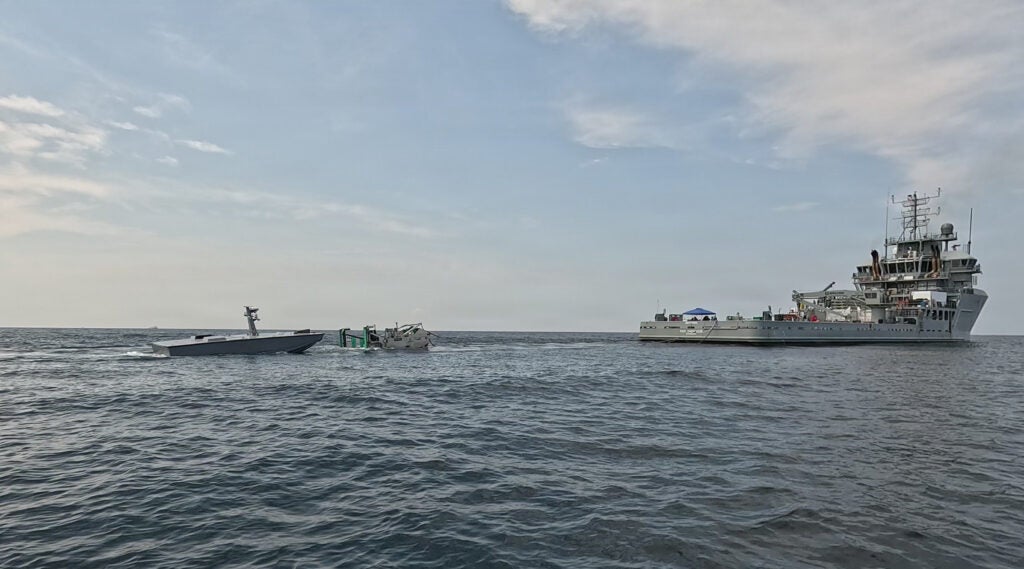A U.S. Navy T38 unmanned surface vessel, left, approaches a towable capture and connection device, center, towed by USNS Vindicator (TSV-5), right, during an Aug. 11 refueling demonstration off Joint Expeditionary Base Little Creek-Fort Story, Virginia. Naval Air Warfare Center Weapons Division’s Blue Water Instrumentation program led the demonstration, part of an effort to keep unmanned vessels on station longer during long-range weapons testing. (Photo: U.S. Navy)